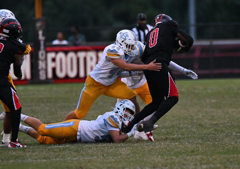 Cape linebacker Robbie Payton, bottom, slows up Red Lion’s Mekhi Corbin, and Zane Coulbourne finishes him off with a drive-stopping tackle.