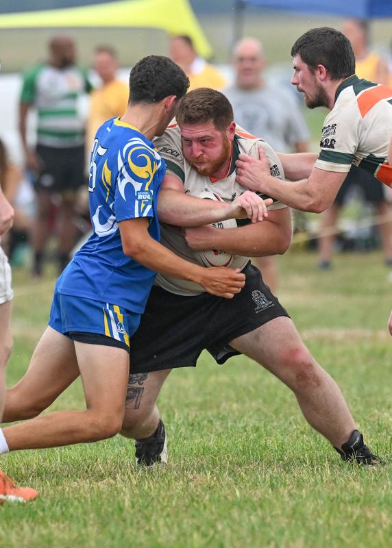 Wilmington’s Alex Politarhos carries the ball and meets his UD opponent head-on as teammate Bobby Bove, right, assists with a push.