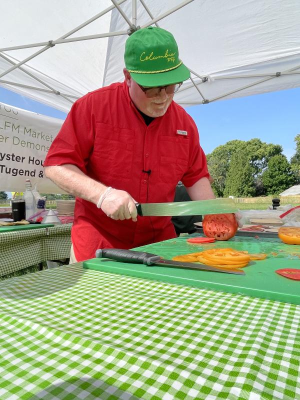 Kindle chef Ian Crandall slices tomatoes really thin as he makes tomato carpaccio with arugula and caper dressing during a cooking demonstration at the market.