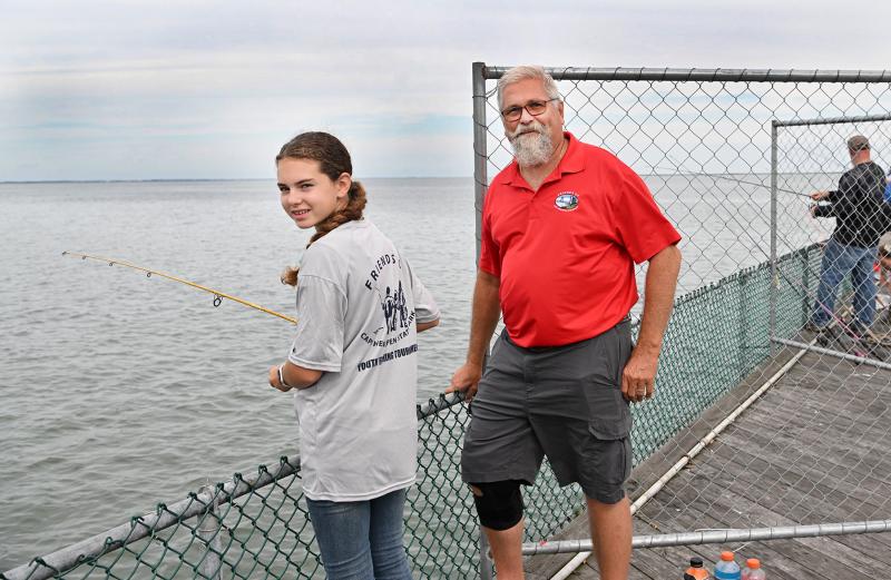 Tournament organizer Dave Frazier, right, speaks with angler Emma Robinson, 12, who is styling in her tournament T-shirt.