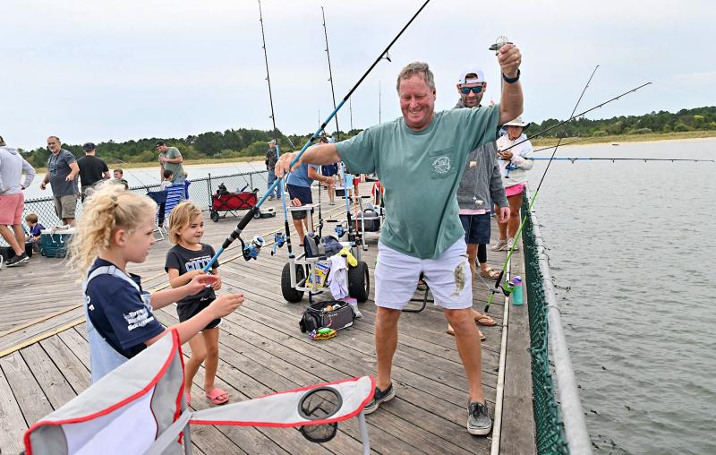 Chloe Poppe, 6, and Ruby Falgowski, 5, get some assistance from Jim “Pop Pop” Laurent as they land their catch.