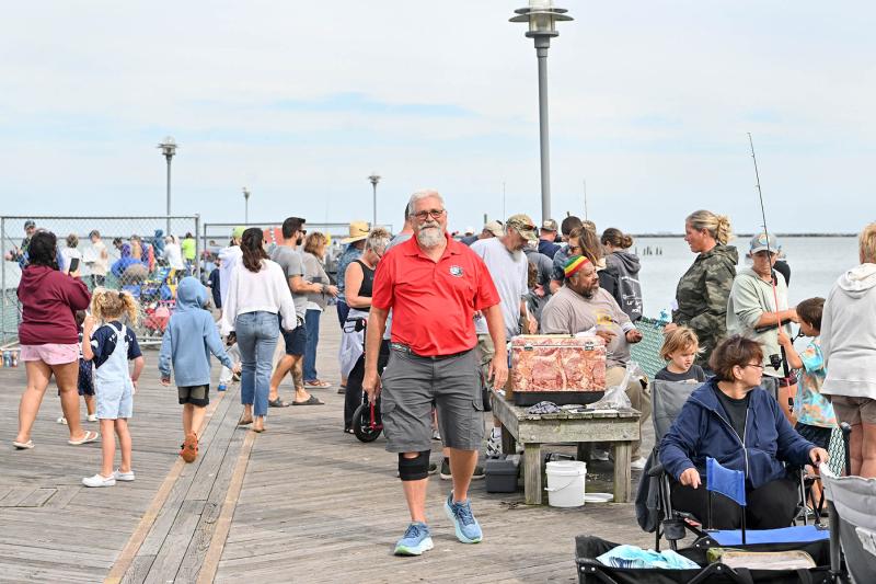 Tournament organizer Dave Frazier, center, has a big smile as he walks around the pier checking on the young anglers.