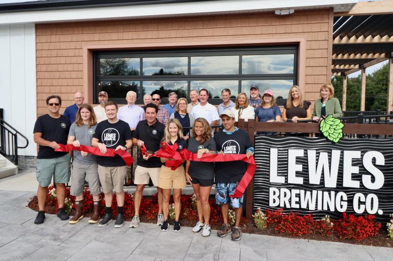 Local leaders joined owners Dave and Christine Jones to cut the ribbon on the Lewes Brewing Company location Sept. 23. Shown in back are (l-r) Sen. Russ Huxtable, D-Lewes; Mark Carter; former Mayor Ted Becker; Steve Letendre; Deputy Mayor Khalil Saliba; Dick Bryan; Lewes Councilwoman Amy Marasco; Jim Smith; Sussex County Councilman Mark Schaeffer; Mayor Andrew Williams; Nikky Fisher; Doug White; Kay White; Tammy Letendre; and Betsey Reamer, Lewes Chamber of Commerce executive director. In front are Drew Oberholtzer, Josh Johnson, Bunky Dorofee, Dave Jones, Christine Jones, Shannon Sehein and Jose Torres.