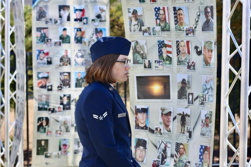 A1C Julia Asmus, a chaplain’s assistant from Dover Air Force Base, looks at photos of some of the fallen service members on the tribute towers. Asmus performed the “Star-Spangled Banner” at the opening ceremony.