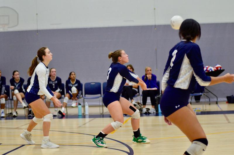 Seahawks sophomore Maya Hastings watches sophomore Grayce Glover prepare to bump the ball as senior Savannah Montgomery provides backup.