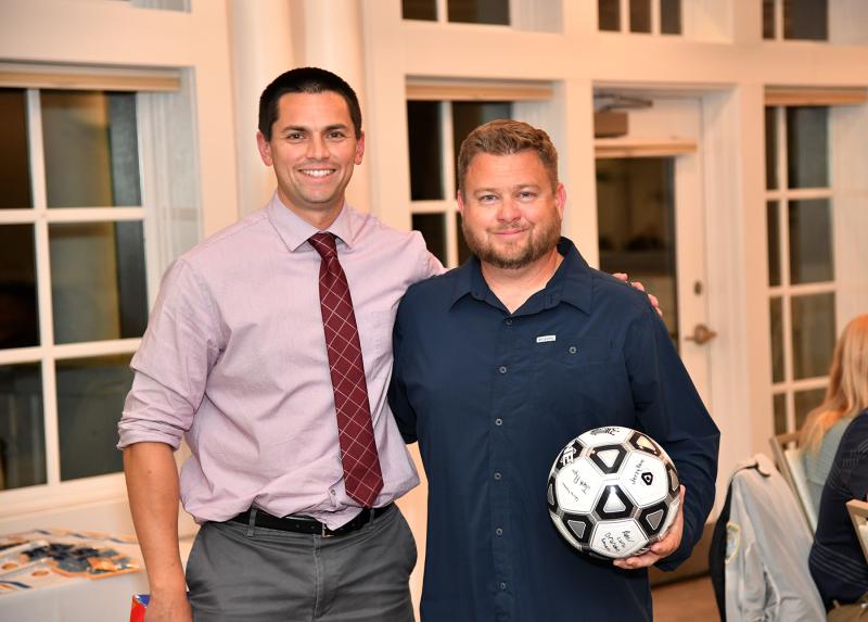 Assistant coach Joe Rupar, left, presents coach Patrick Kilby with a team-signed ball for his 100th victory.