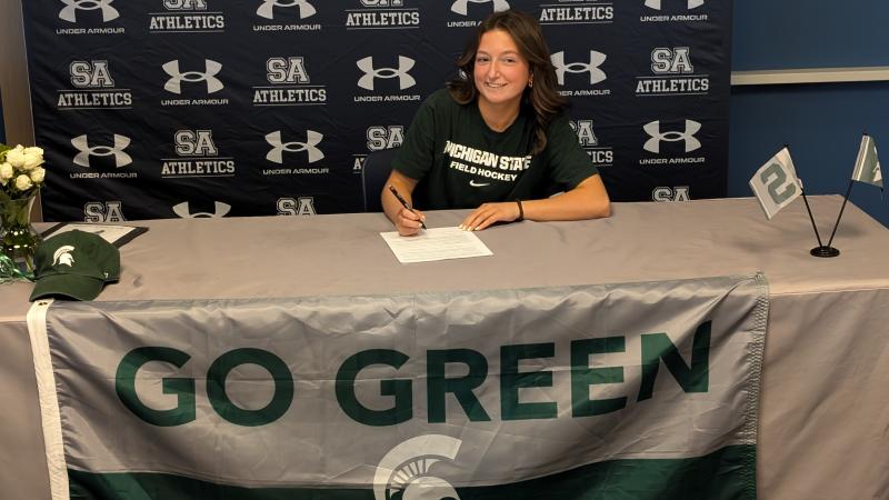 Rilyn Lehman smiles as she signs her letter of intent to attend Michigan University in East Lansing, Mich., and play field hockey in the ultra-competitive Big Ten.
