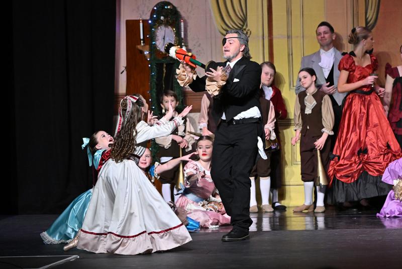 Mysterious godfather Drosselmeyer, played by Braeden Swain, presents the nutcracker to Clara, played by Kinley Johnson.
