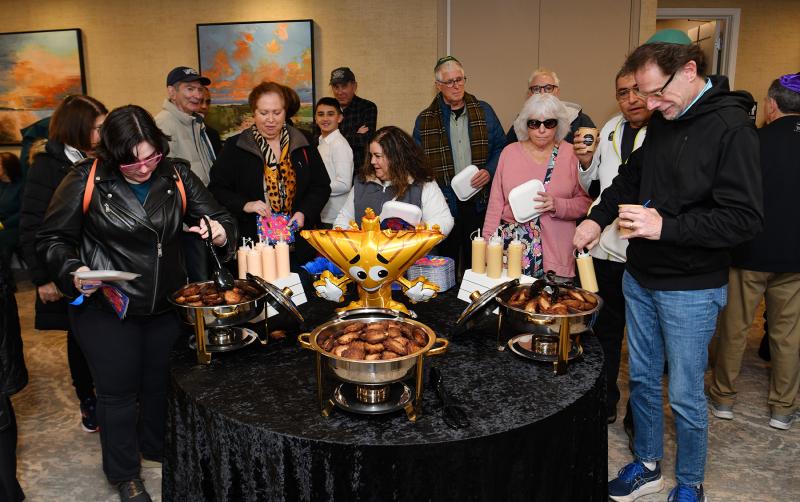 A big crowd is ready to enjoy the hot latkes topped by applesauce and spicy mayo, along with hot cocoa.