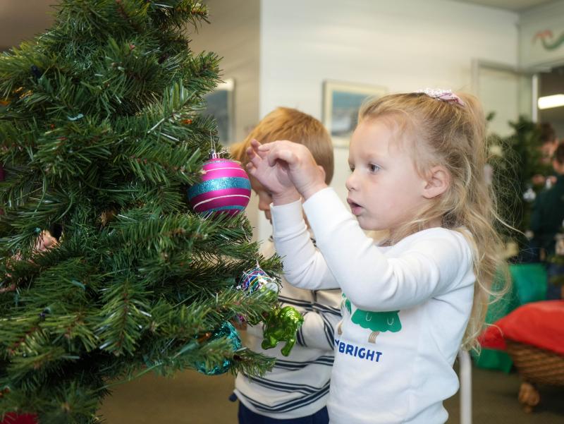 Olive Manieri, 3, hangs an ornament on the tree her family is decorating this year for a family in need.