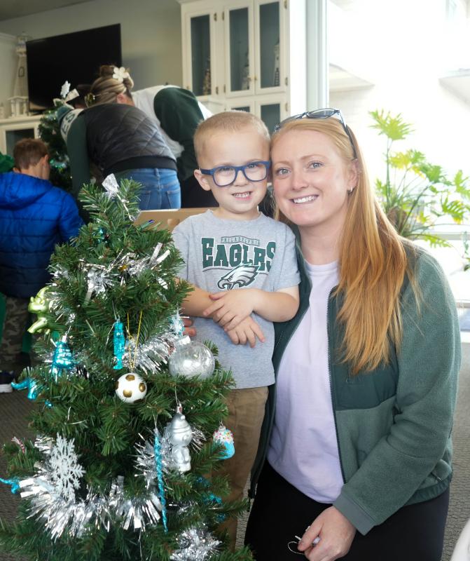 Kaitlyn Freel smiles with her 3-year-old son Beau next to the tree they decorated this year for a family in need.