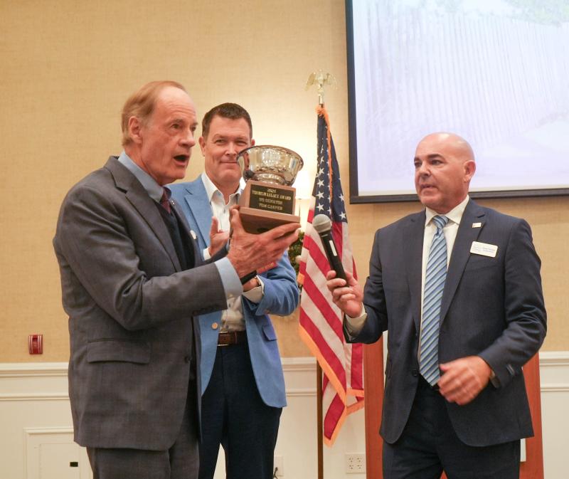 Sen. Tom Carper holds up the Tourism Legacy Award he received from SDT Chair Matthew Parker and Executive Director Scott Thomas.