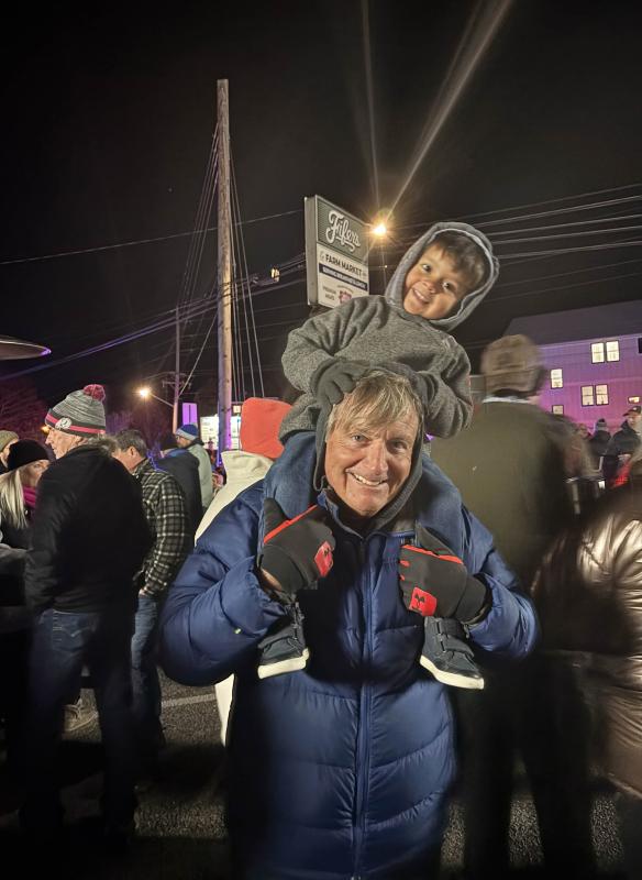 Tom Natoli smiles with his 3-year-old grandson, Hudson Contreras, on his shoulders at the Dewey Business Partnership tree lighting.