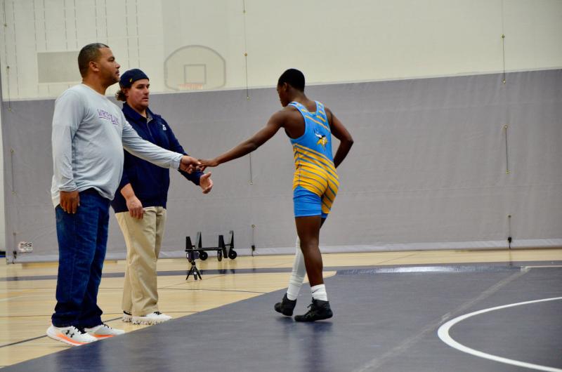 Beacon eighth-grader Noah Flechier shakes hands with Sussex Academy coach Deon Brunskill and Dominic Patton after his victory.