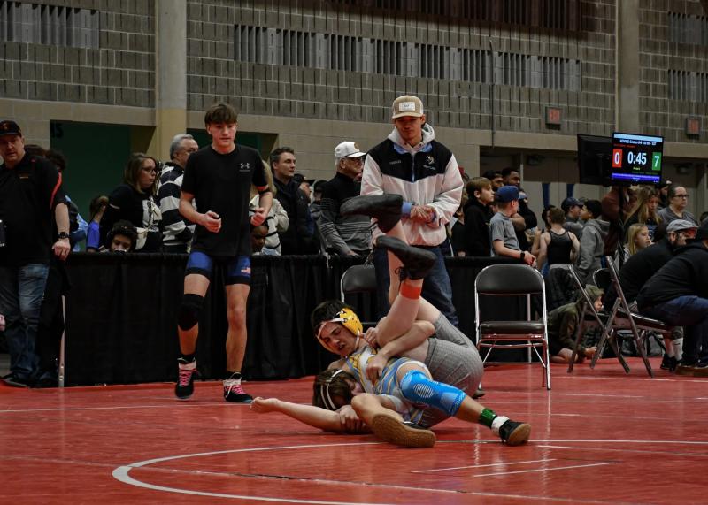 Ryder Gomez, left, and coach Hayden Wheeler, a 2024 Cape graduate, look on as Caleb Olmstead turns his opponent into a pretzel.