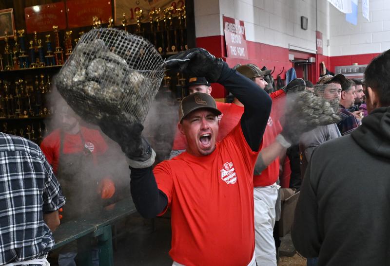 Jake Ricker, president of Georgetown Fire Company, carries a basket of oysters to awaiting shuckers.