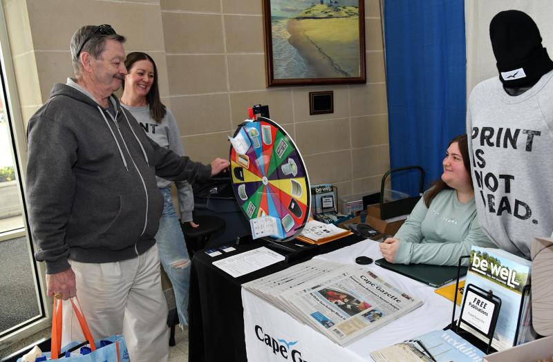 Joseph Opdenaker wins a Cape Gazette prize from the wheel spin. Shown from the publication are Lauren Zaniewski and Liz Tedley.