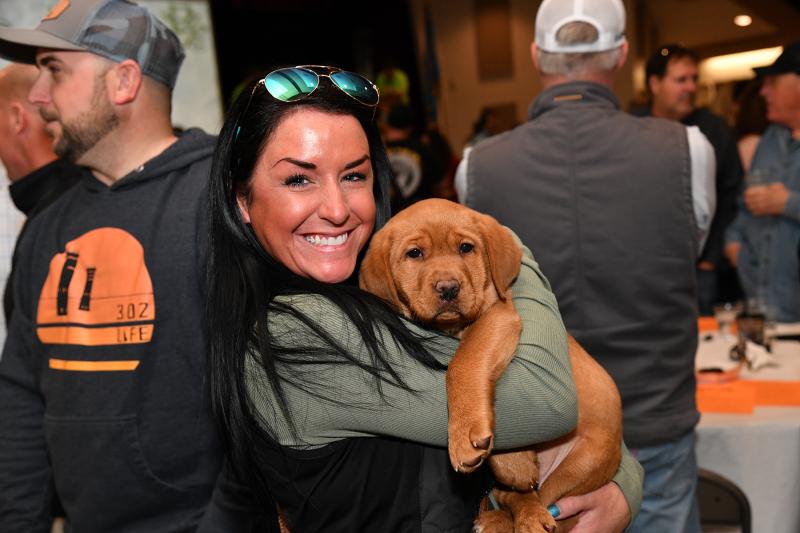 Tara McCaffrey gives the red fox lab some love before the live auction. The pup’s winning bid was $5,000.