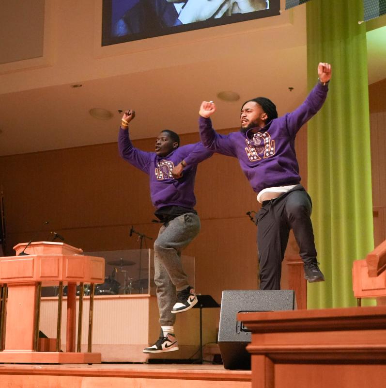 A team from the Psi Iota Chapter of Omega Psi Phi, a historically Black fraternity, performs a hop, a dance style characterized by rhythmic jumping.