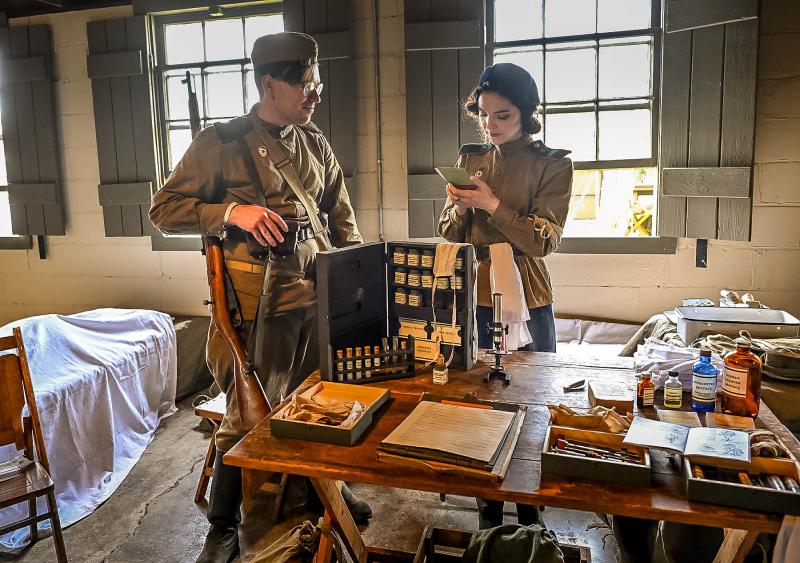 Ben Ahlert gives symptoms of his injury to Soviet field medic Hannah Motter during the 2025 Delaware Defense Day at Fort Miles.