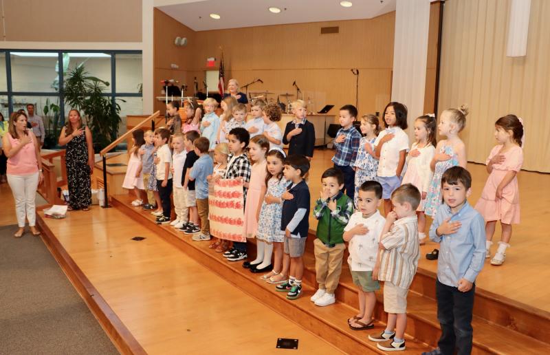 Students and teachers from the Penguin, Starfish and Pelican classes recite the Pledge of Allegiance at the start of the ceremony.