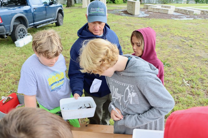Colton Kroll, Lincoln Wilson and Brody Chandler-Thompson check out some crayfish that Todd Fritchman pulled from a pond.