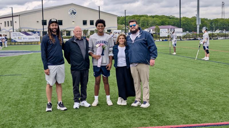 Jahmari Davis is escorted by his grandparents Mariana Cebollcro and Charlie Guggenheimer, and joined by his defensive coach Ben Weathersby, left, and head coach Andrew Fox.