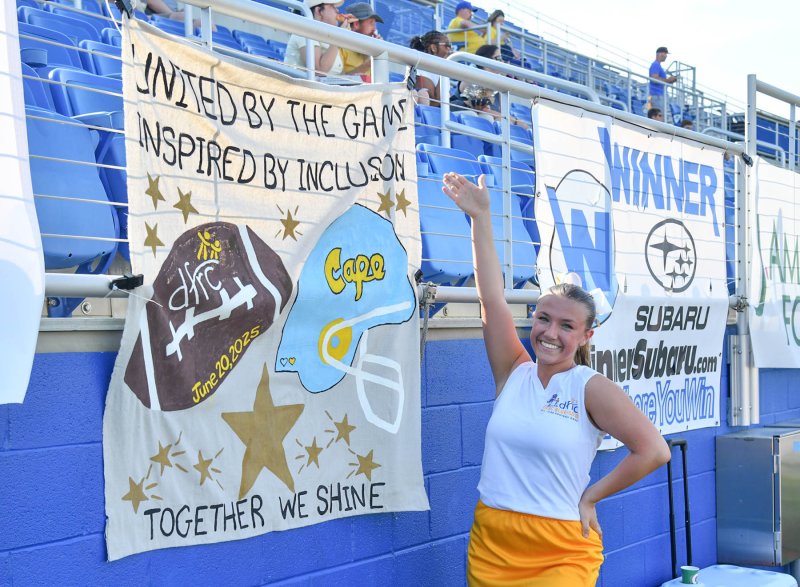 Gold cheerleader Carly Favoroso of Cape displays her poster that hung on the home gold side of Tubby Raymond Field.