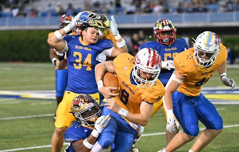 Tate Walls (Laurel) carries the ball for the Gold squad while Blue’s Mitch Cummings (Sallies) loses his helmet.
