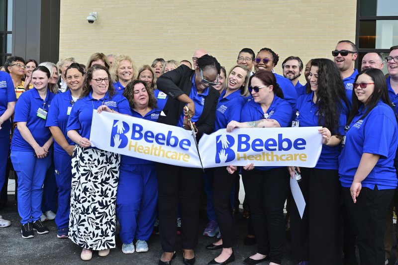 Dr. Joyce Robert, Family Medicine Residency Program director, is surrounded by employees as she cuts the ribbon for the grand opening.