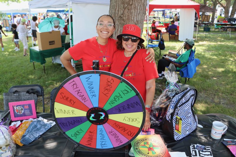 Miranda Mathias, left, and Audrey Mathias are in charge of the prize wheel. Visitors could spin to win their choice of an item on the table.