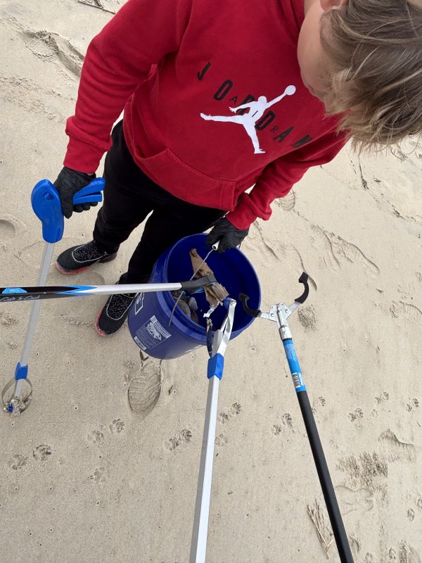 Beacon student Andrew Bordner holds the trash bucket ready for cleanup finds at Cape Henlopen State Park.