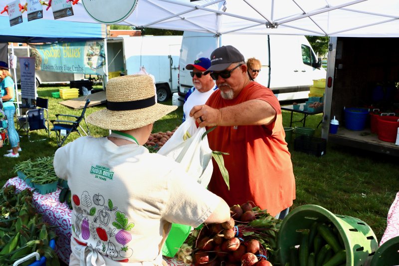 Tommy Eliason of Kalmar Farm hands over local corn to Linda Darling, an HLFM board member. Eliason is one of the vendors who has been at the market since the beginning. Besides the corn, watermelons and tomatoes are big sellers at Kalmar Farms’ tent.
