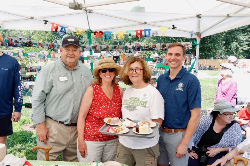 Historic Lewes Farmers Market co-founder Helaine Harris holds a tray of cake served to patrons at the market’s 20th birthday celebration. Shown are (l-r) Don Clifton, Delaware agriculture secretary; Lewes Mayor Amy Marasco; Helaine Harris; and Chris Brosch, Delaware agriculture department deputy secretary.