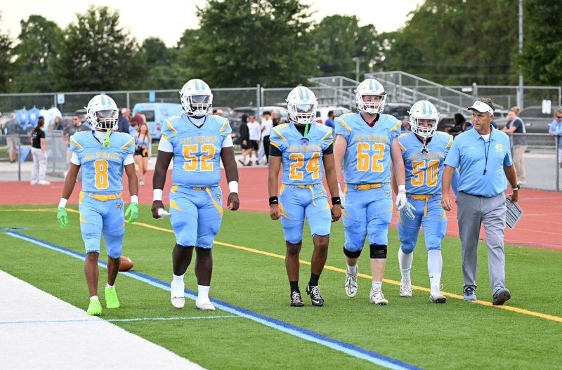 Cape coach Chip Knapp walks out on Legends Stadium turf with his 2025 captains. Shown are seniors (l-r) Ty Handy, Tremaine Batson, Quardell Richards, Liam Ramsey and Robbie Payton.