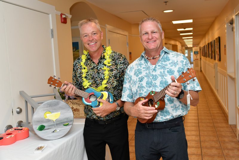 Chris Hughes, left, and Kent Swarts show off their inner Eric Clapton with the hand-painted ukuleles at the silent auction.