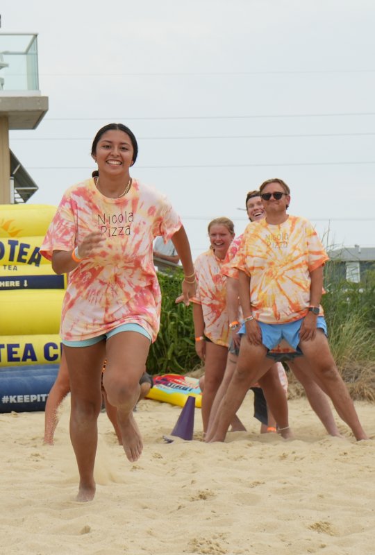 Nicola Pizza’s Katherine Portillo runs toward the bat during the dizzy bat relay. Cheering her on are (l-r) teammates Zoe Musil, Connor Christie and Brendt Nuedstater.