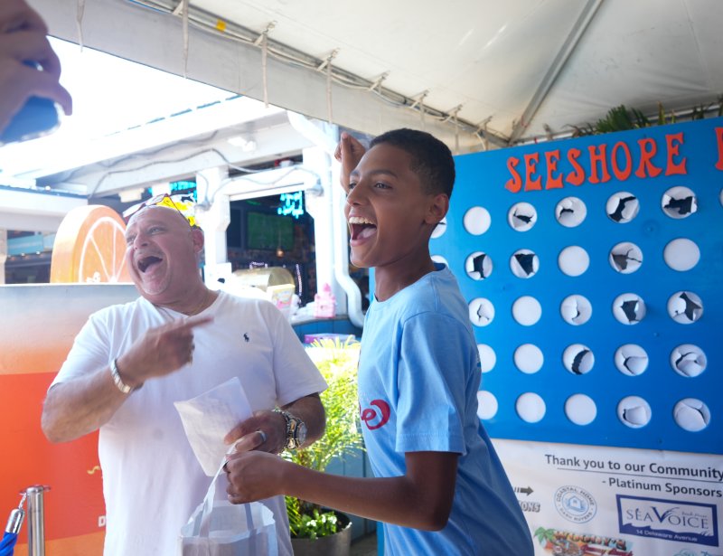 Celebrating his prize from the punch board is Isaac Nyandusi. To his left is DJ Manny Mann, the emcee for the event.