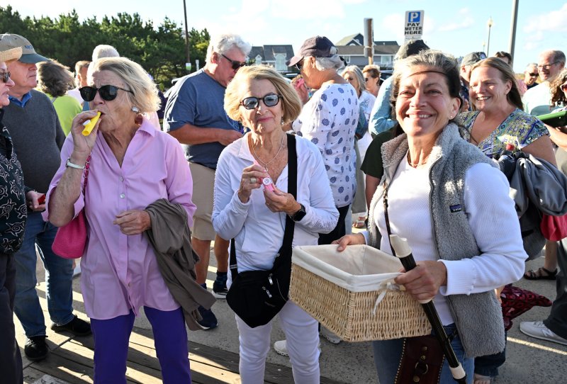 Marylou Kupfer, left, and Jackie Dolan get their kazoos from Rehoboth Beach Historical Society and Museum Executive Director Heidi Nasstrom Evans.