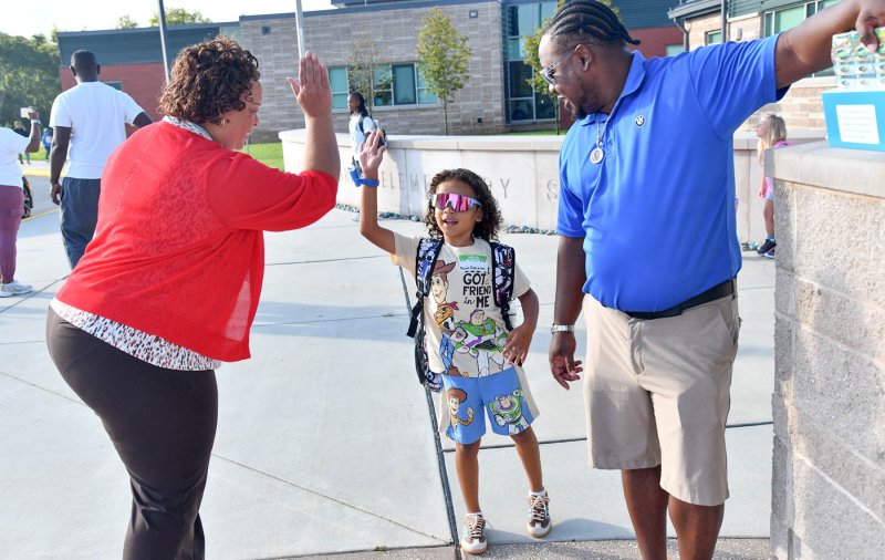 Mason Robinson, 6, gets a high five from district office staff member Lisa Morris while he and his dad Nate wait for school to open at H.O.B. DAN COOK PHOTO