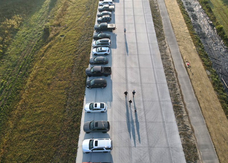 The early morning sun creates long shadows of people as they walk to the starting line at the North Millsboro Bypass 5K.