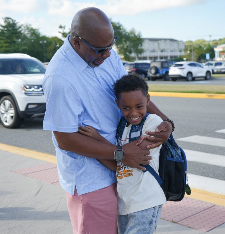 Rehoboth Elementary paraeducator Gilbert Maull gives second-grader Alvin Woodhouse a hug to start his first day of school. ELLEN MCINTYRE PHOTO