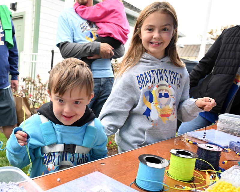 Braxtyn Burger, left, and Kinsley Murray of Braxtyn’s Crew assemble a necklace at the craft activities booth.