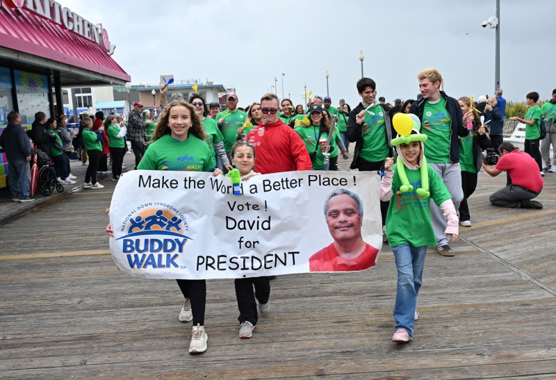 Friends carry the commemorative banner for David Samson, who inspired the Boardwalk Buddy Walk before his death in 2018.