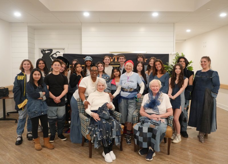 Cape fashion students and their teacher smile with the Lodge residents who modeled the students’ designs in March 2025.