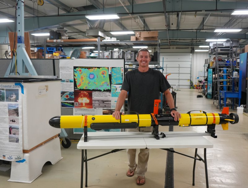 Grant Otto stands with one of the autonomous underwater vehicles he uses in his field work to gather data and map underwater areas.