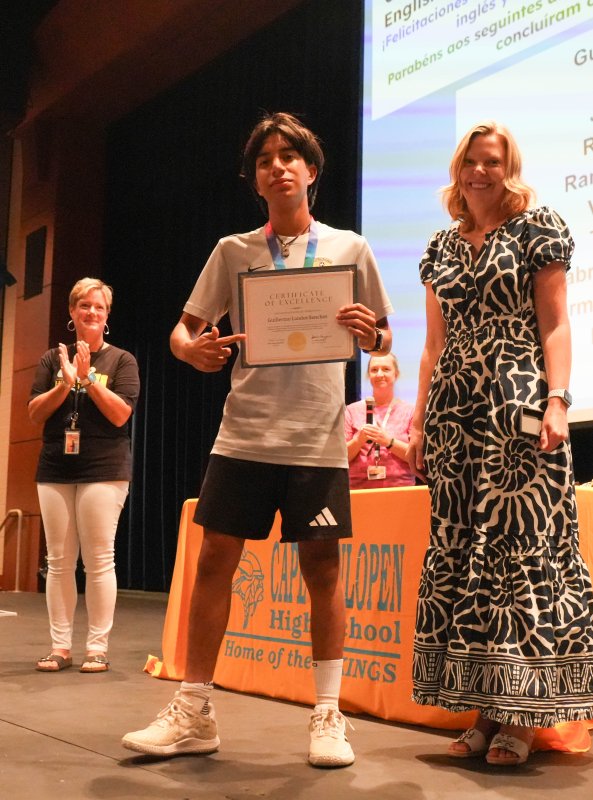 Cape student Guillermo Landos Sanchez proudly holds the certificate he received from Assistant Principal Jessica Hazzard for demonstrating English proficiency. In the background are (l-r) teachers Carla Yngve and Casey Cashdollar.