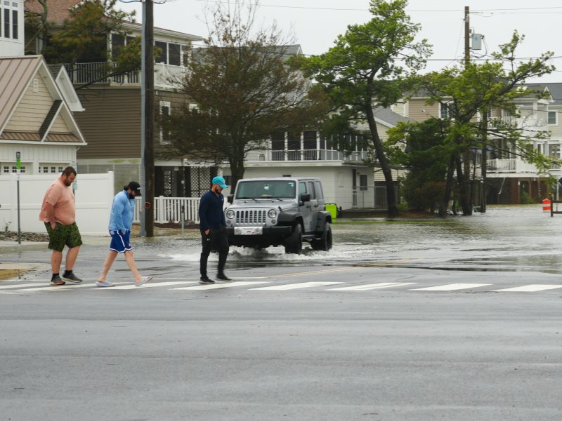 Only a few people are out walking around Dewey on Oct. 12 amidst the wind and rain. Behind them, a Jeep navigates a flooded Read Avenue. ELLEN MCINTYRE PHOTO