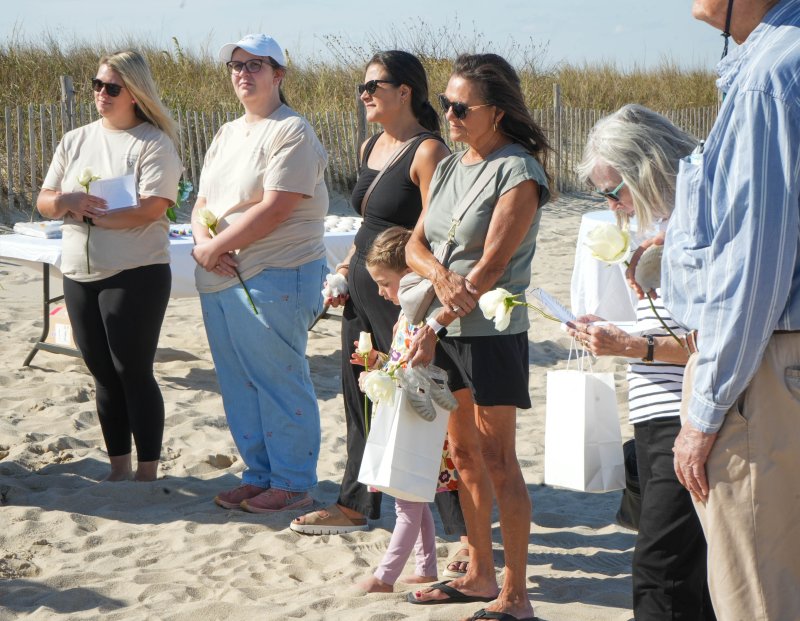 Attendees hold white roses during a memorial service on the beach after the walk Oct. 19. Shown are (l-r) Beebe’s Kelsi Warrington and Grace Sweetman, along with Elise Bruno, Aela Bruno, Marilyn Glisci and Diane and Pete Dirks.