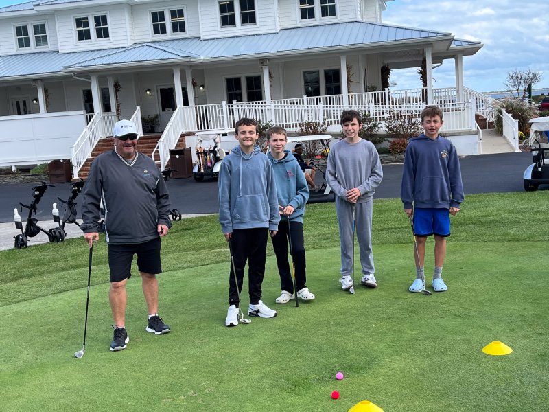 Coach Tim Gabbard helps Beacon students (l-r) Robert Cowden, Reese Webb, Thomas Taylor and Lucas Skonieczki learn about the science of putting.